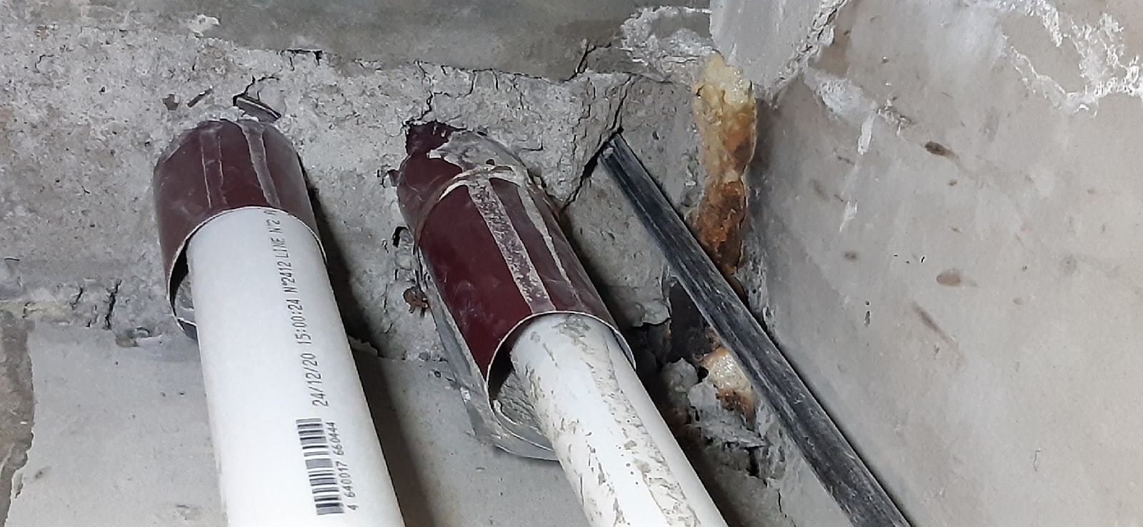 Повреждения бетона и зазоры вокруг проходов труб при осмотре квартиры в новостройке